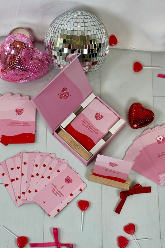 Self Love Hair Club 54 card affirmation deck with wooden stand and gift box, heart-themed cards, disco balls, and lollipops on a white background.